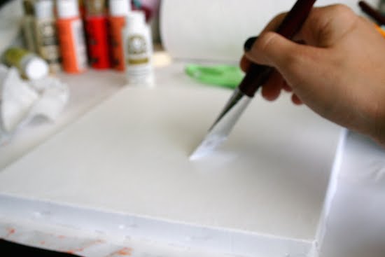 Painting a canvas with white acrylic paint