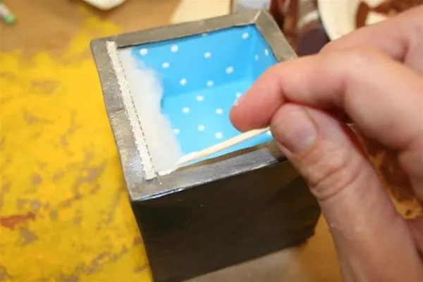 Gluing trim onto the shadowbox ornament with a toothpick