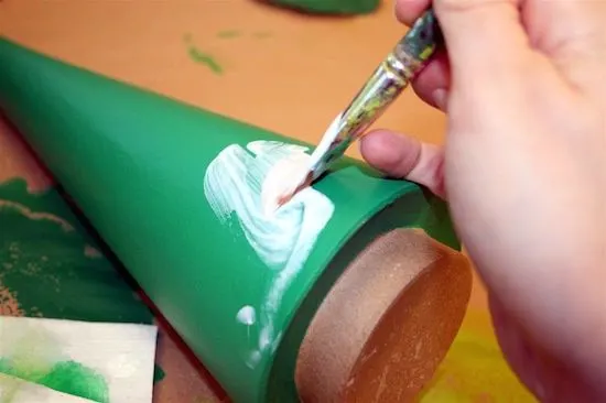 Applying Mod Podge to the green painted paper mache tree