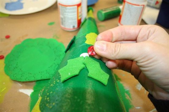 Gluing the felt holly leaves and red buttons onto the cone tree