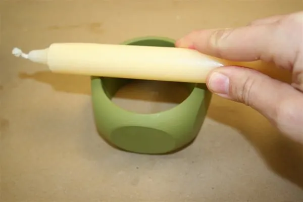 rubbing a wooden bangle bracelet with a wax candle