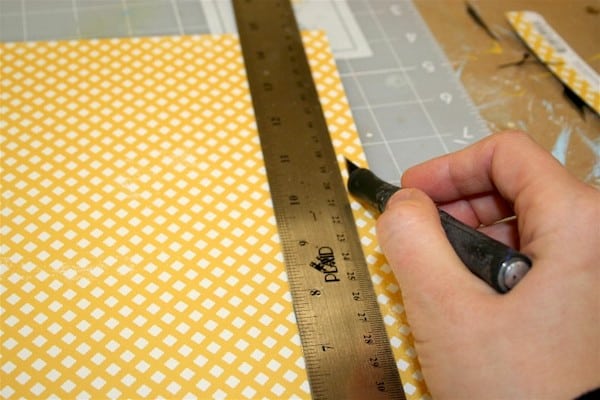 Trim a piece of scrapbook paper with a craft knife and metal ruler