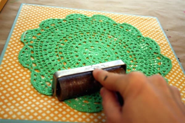 Roll out a doily on canvas with a brayer