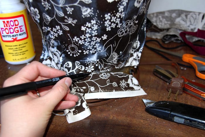 Trimming the fabric around the lamp base with a craft knife
