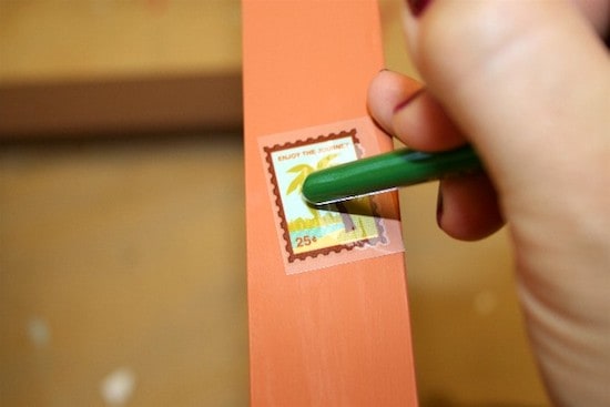 Applying a rub-on to the chair leg with a paintbrush handle