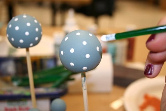Dotting painted wood balls with a paintbrush handle dipped in white paint
