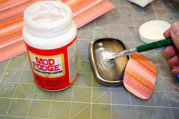 Applying Mod Podge to the inside of the buckle using a paintbrush
