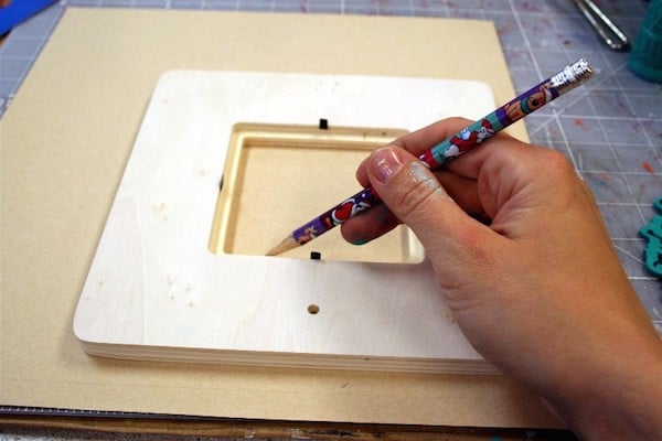 Tracing a wood frame with a pencil on the back of scrapbook paper