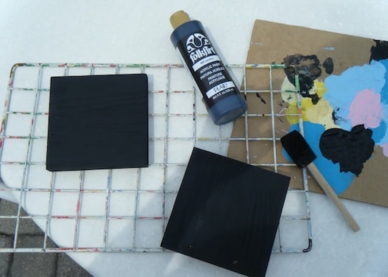 Wood pieces painted with black paint and drying on a rack