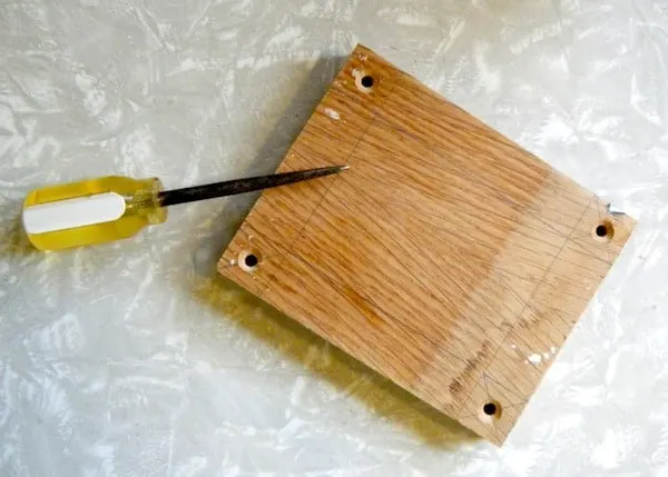 Piece of plywood with holes drilled in it along with a screwdriver