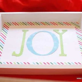 Paper letters spelling JOY laying on the white tray