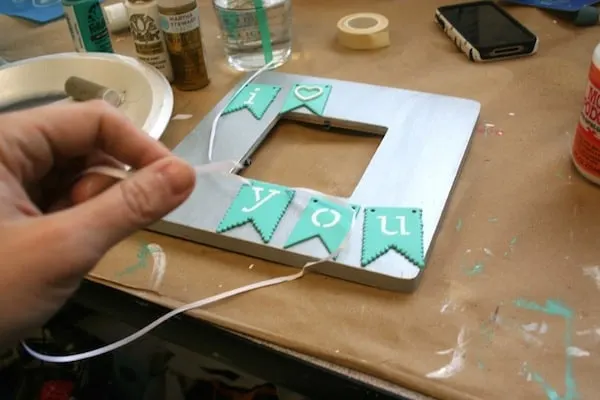 Cut piece of white ribbon with an i love you frame in the background