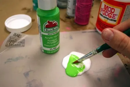 Mixing green paint and Mod Podge with a paint brush