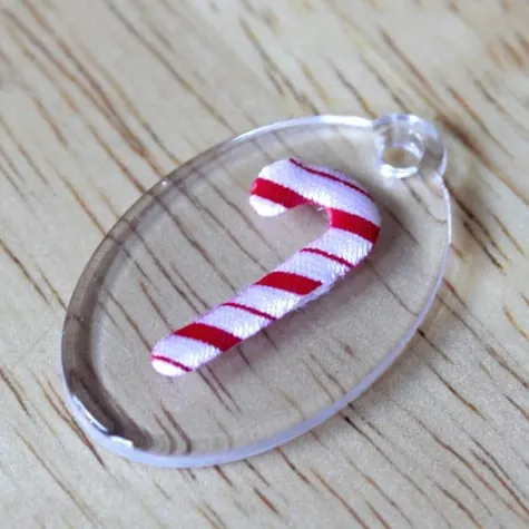 Mini candy cane on top of an acrylic oval