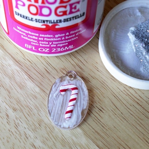 Mod Podge Sparkle painted on top of a candy cane ribbon piece in the center of an acrylic oval