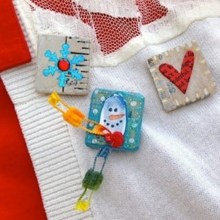 Cute Christmas pins for kids pinned onto a white sweater