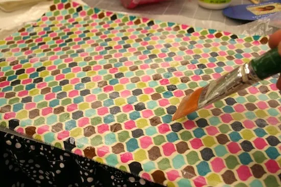 Placing a layer of Mod Podge on the fabric with a paintbrush