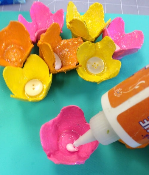 Gluing buttons into the bottoms of the egg carton flowers