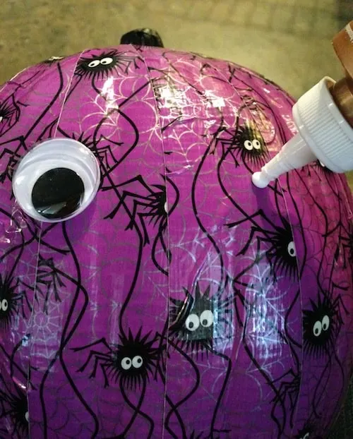 Applying googly eyes to the pumpkin with craft glue