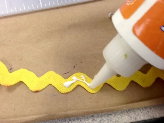 Putting craft glue on a piece of yellow ric rac