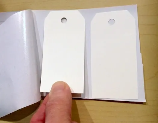 Placing the white gift tags onto the dry erase tape