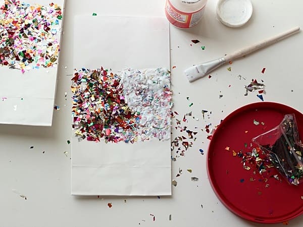 Metallic confetti on top of a white paper bag covered in Mod Podge