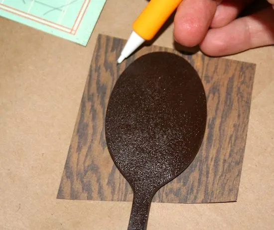 Tracing a spoon on scrapbook paper with a pencil