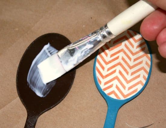 Adding Mod Podge to the spoons with a paintbrush