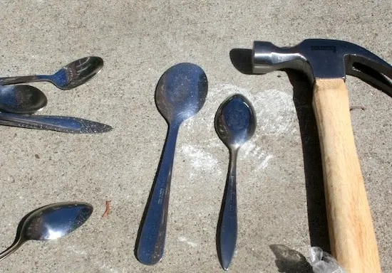 Spoons and a hammer laying on the concrete ground