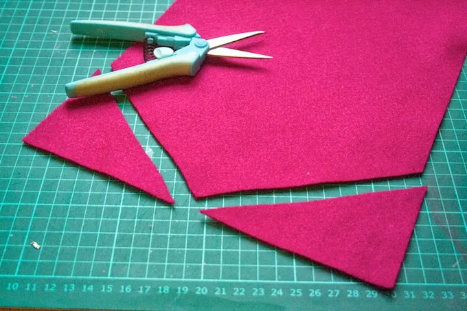 Magenta felt cut to a point laying on a cutting mat with scissors