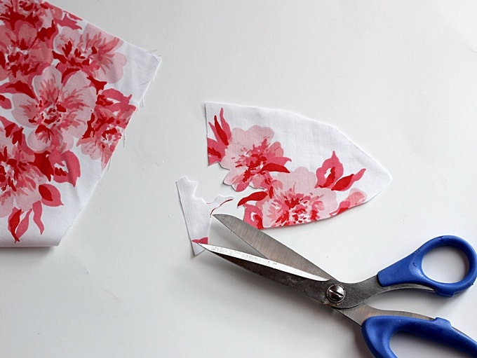 Piece of fabric with a floral print partially cut out with a pair of scissors