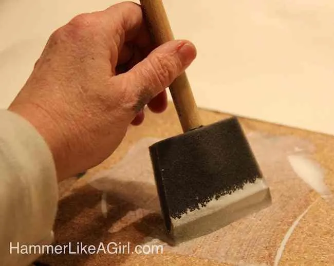 Applying Mod Podge to the particle board with the foam brush