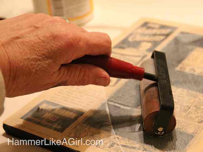 Rolling a brayer across the top of the pages on the particle board