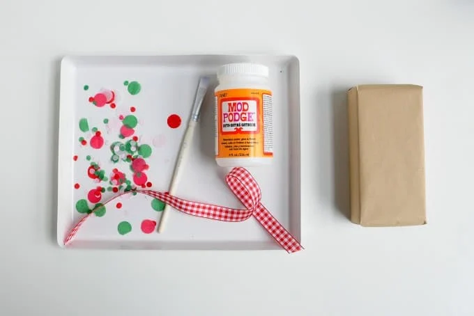 Confetti, wrapped gift, paintbrush, ribbon, and Mod Podge