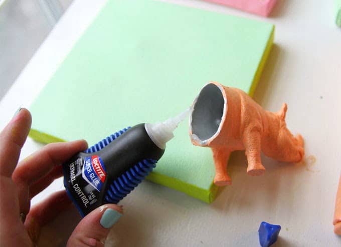 Placing Loctite glue on the front half of a rhinoceros plastic animal 