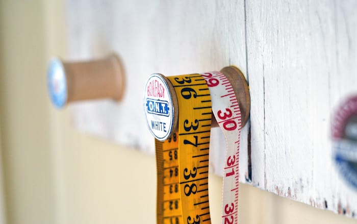 Closeup of a wooden spool hanger holding measuring tapes