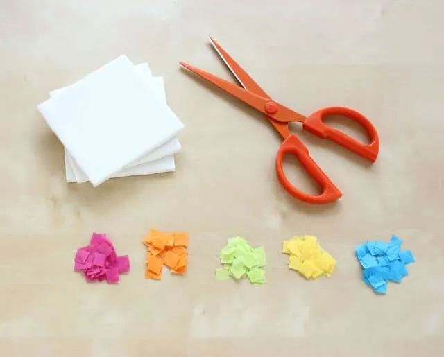 Five piles of colored tissue paper squares, a pair of scissors, and tiles