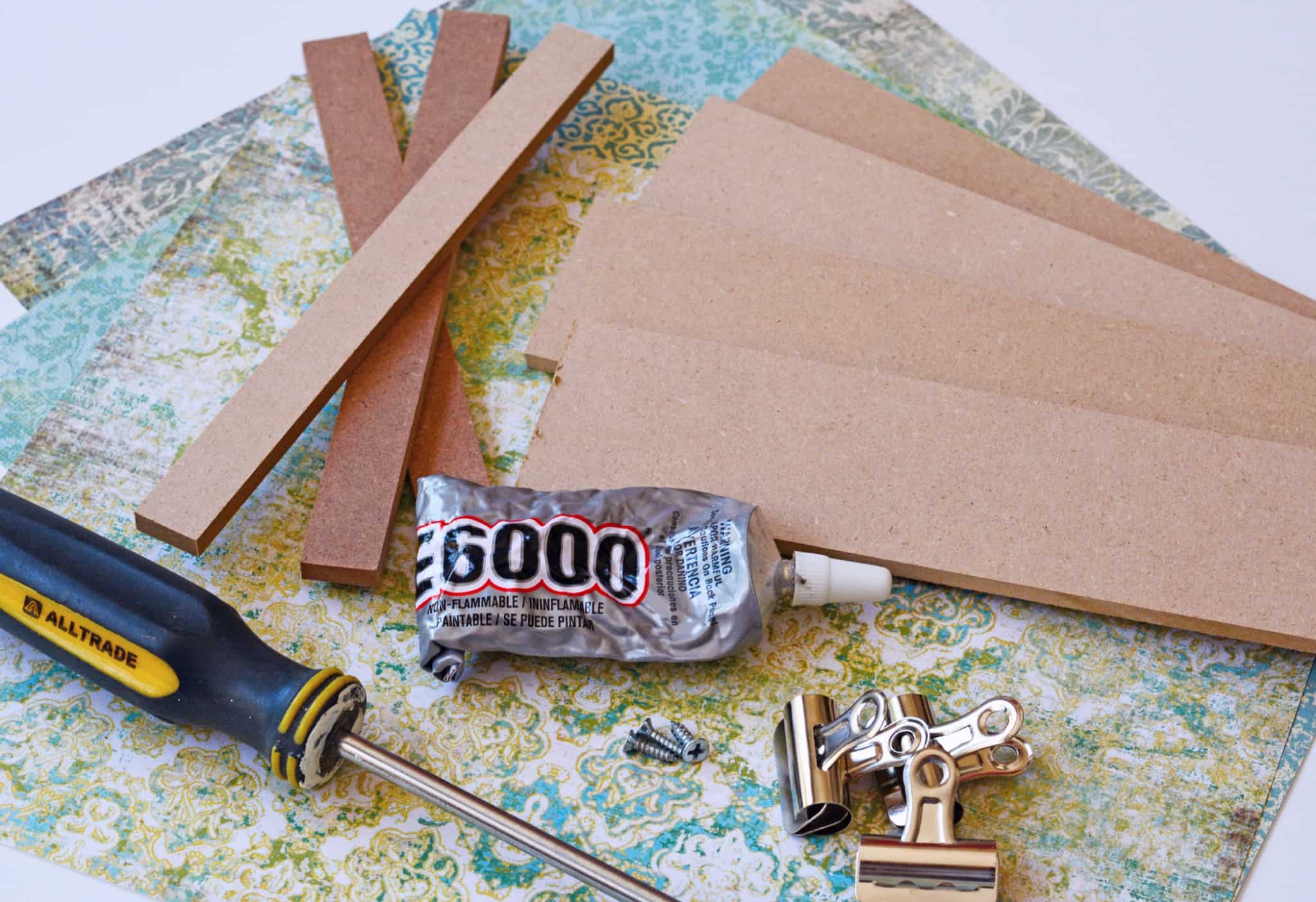 Scrapbook paper, craft wood strips, screwdriver, screws, E-6000, bulldog clips