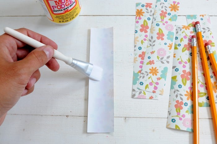 Painting Mod Podge Matte on the back side of a piece of paper with a white paintbrush