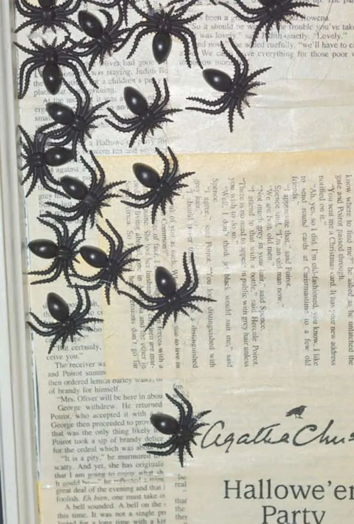 Plastic spiders glued to book pages on a Halloween window
