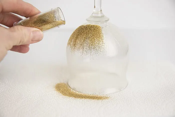 Hand sprinkling glitter on wet Mod Podge on glass