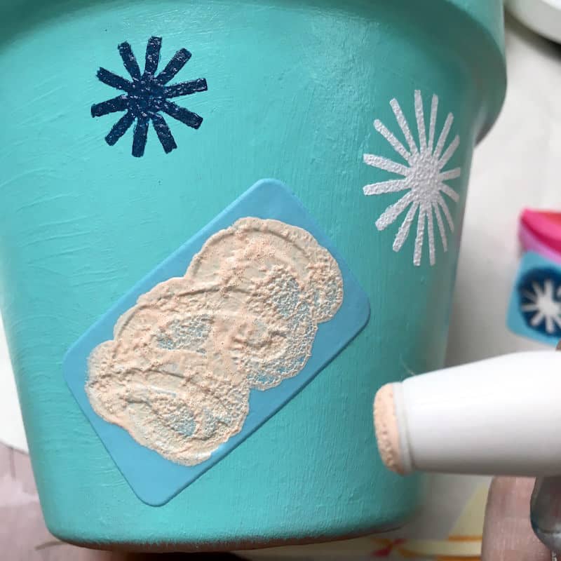 Painting over a stencil to decorate a clay pot