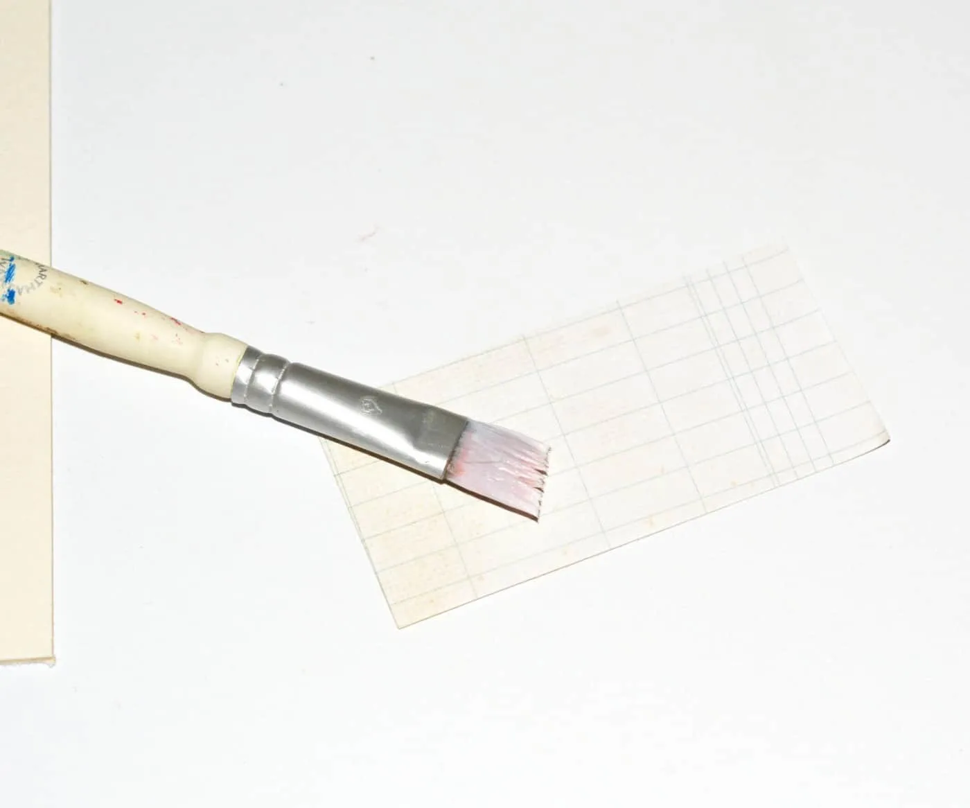 Brushing Mod Podge on the back of a piece of paper with a paintbrush