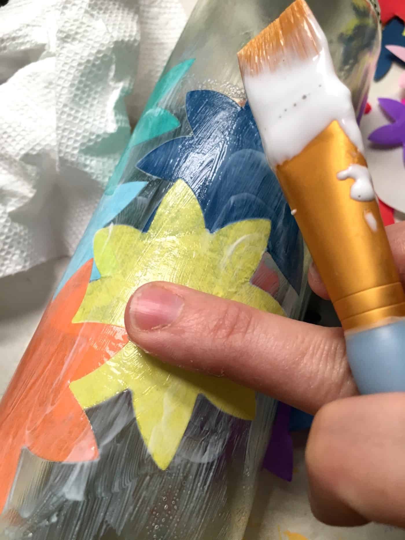 Finger smoothing tissue paper shapes down onto the bottle