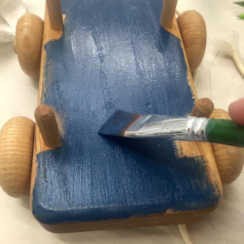Painting the base of the wood toy with navy craft paint