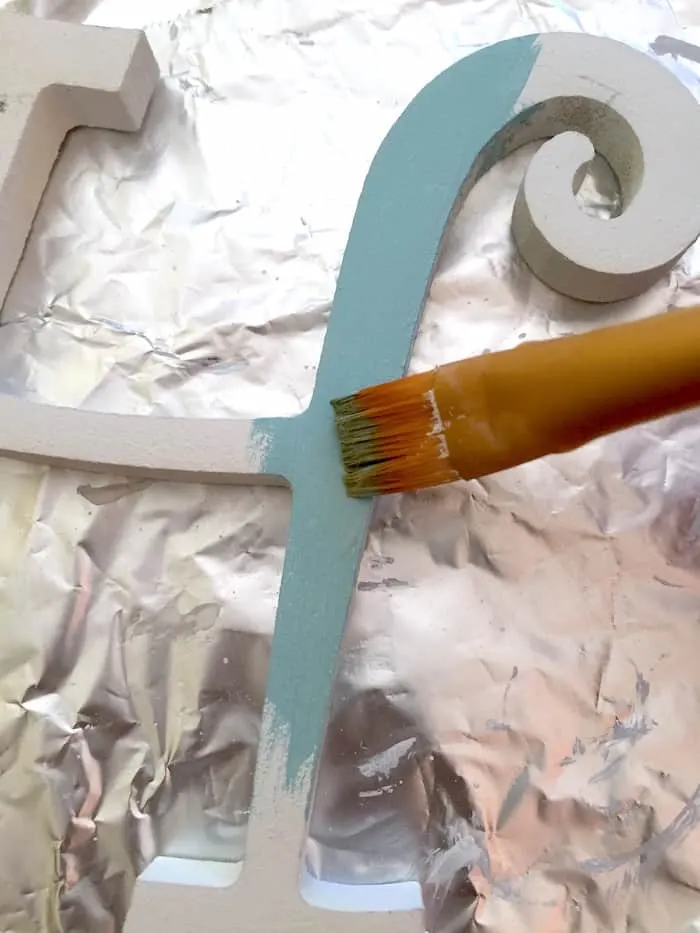 Painting a wood letter H with blue paint