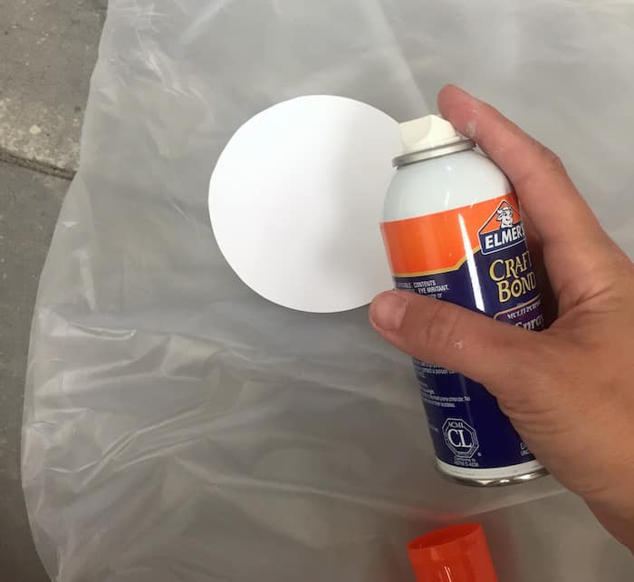 Spraying a paper circle with Elmer's Craft Bond spray adhesive