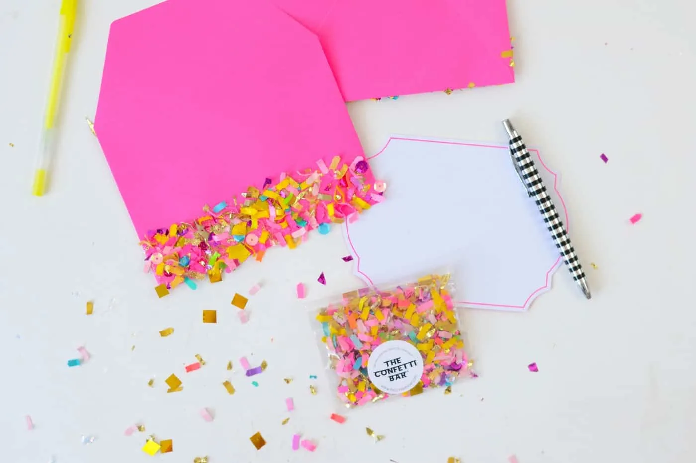 DIY confetti envelopes with a white label, striped pen, and package of confetti