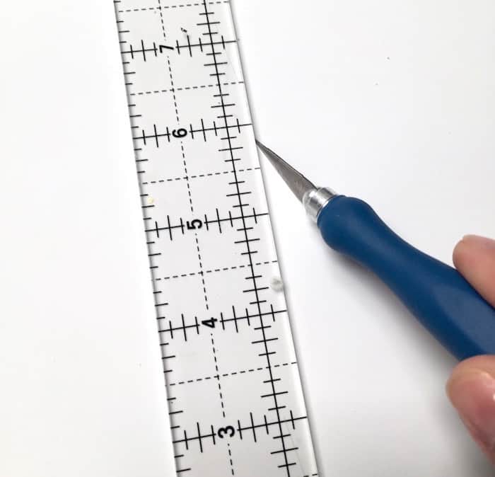 Craft knife cutting paper next to a ruler