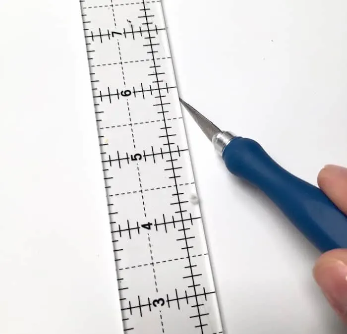 Craft knife cutting paper next to a ruler